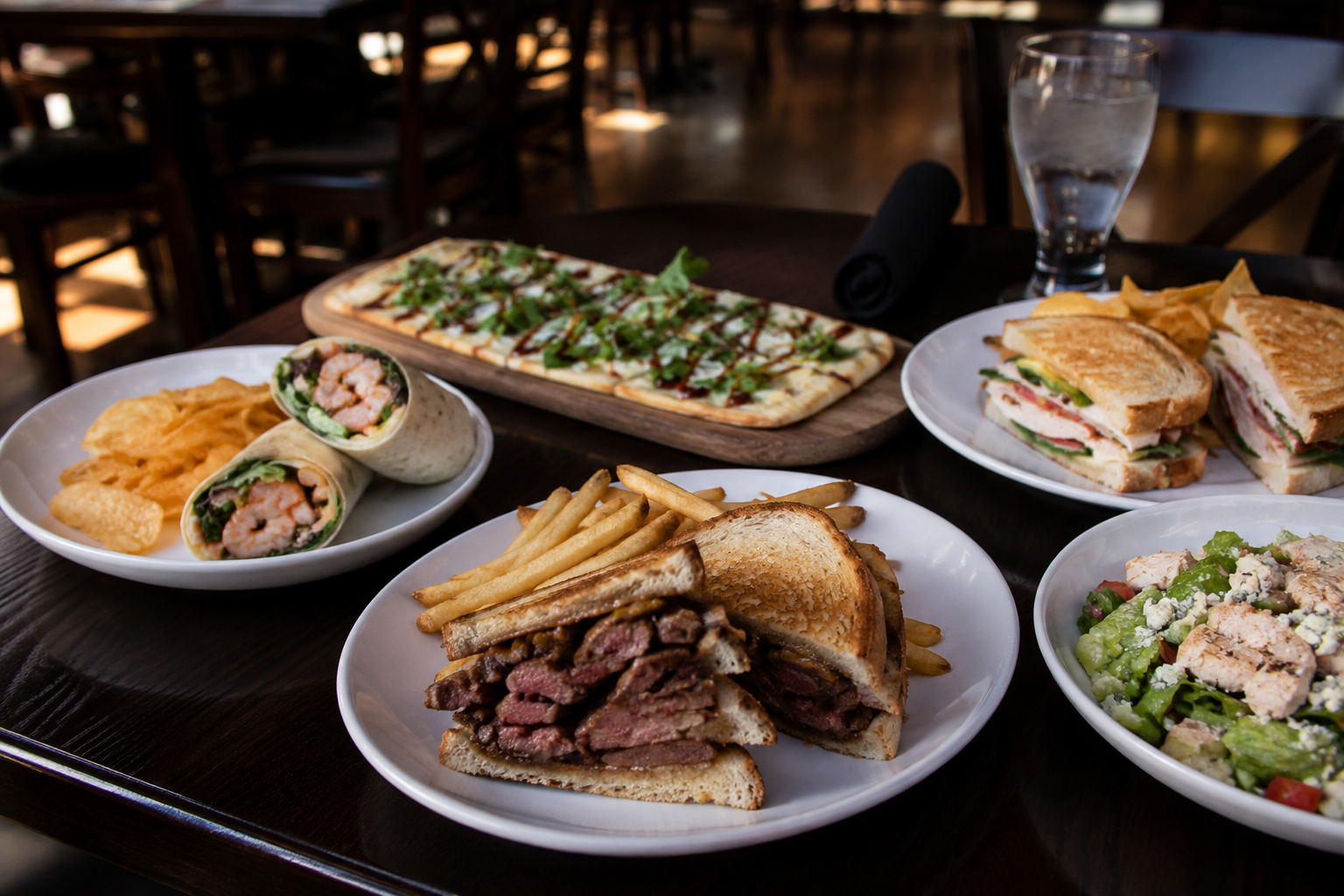 Friday lunch spread at The Board Room in Libertyville featuring a steak sandwich, shrimp wrap, artisan flatbread, fresh salad, and turkey club sandwich.