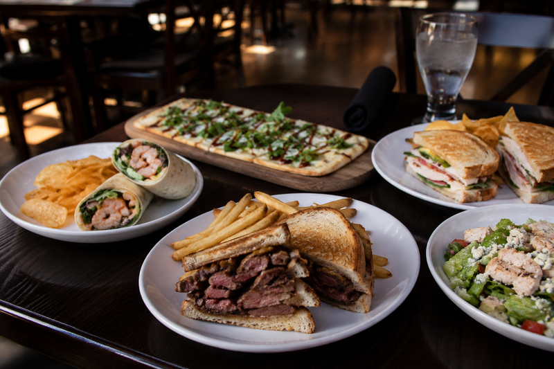 Friday lunch spread at The Board Room in Libertyville featuring a steak sandwich, shrimp wrap, artisan flatbread, fresh salad, and turkey club sandwich.